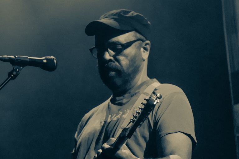 Swervedriver performing live at Lion Arts Factory in Adelaide, featuring frontman Adam Franklin on electric guitar under moody blue stage light.